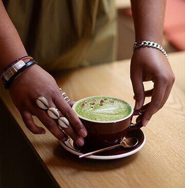 Tasse de latte au moringa posée sur une table au café afro vegan Wassaï